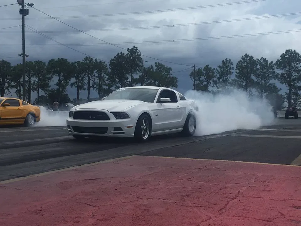 A Mustang sitting in its own tyre smoke at the track