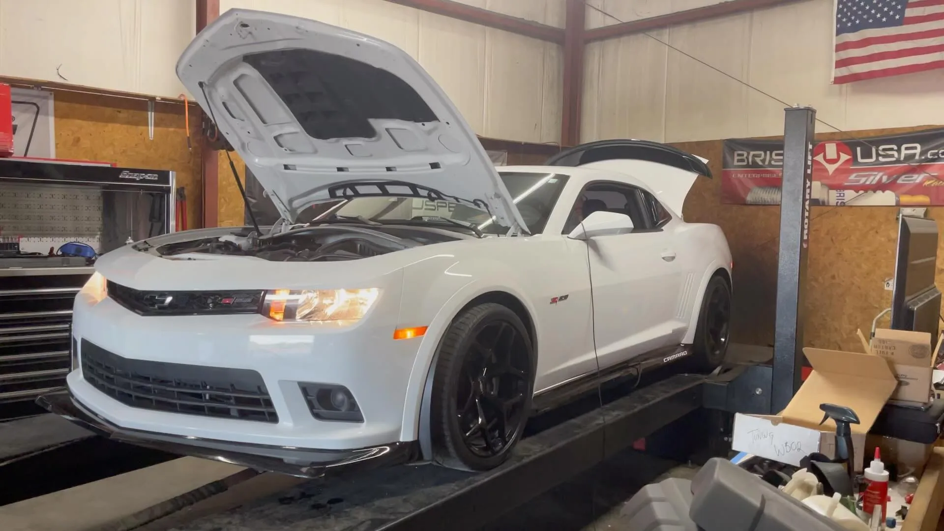 A white Camaro SS on the lift with the hood up