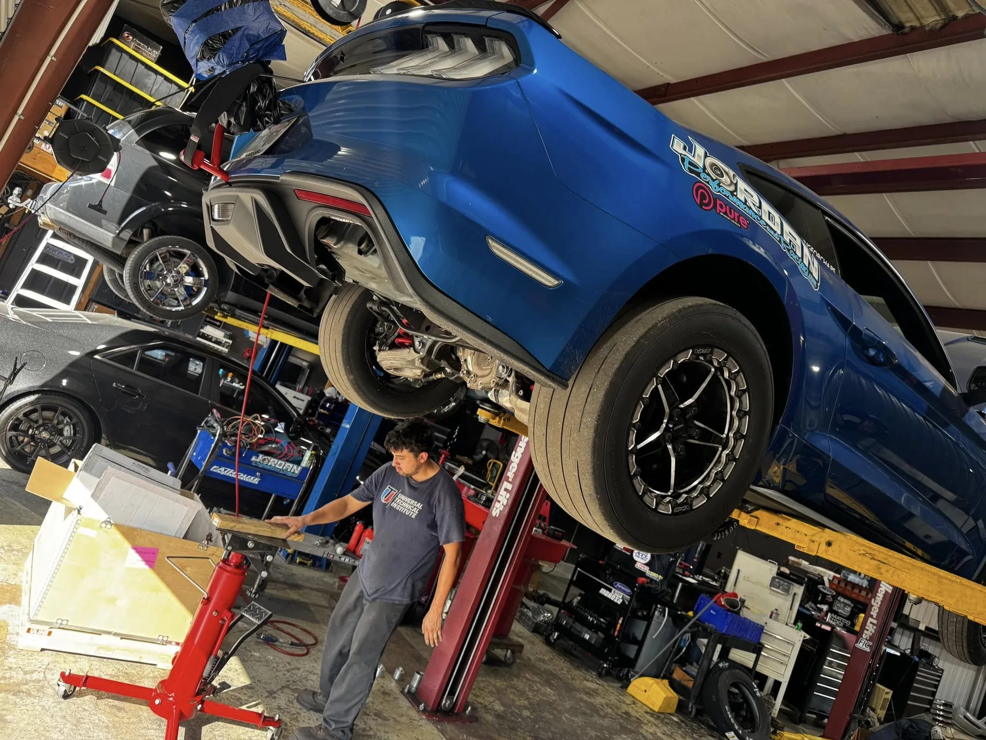 A blue Mustang on the lift in the shop