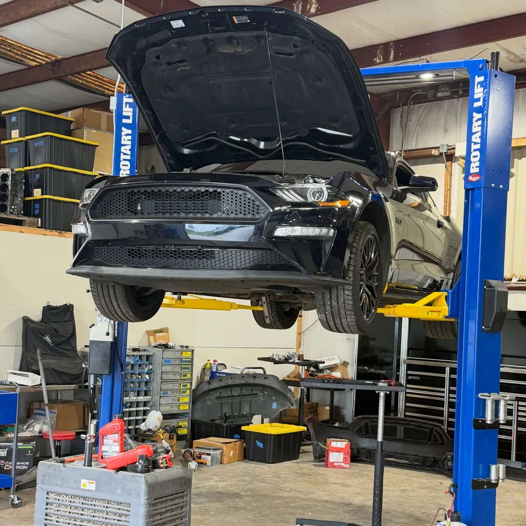 A black Mustang GT up on the two post lift with the hood open